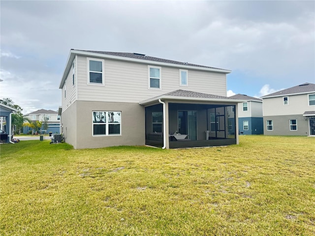 rear view of house featuring a sunroom and a yard