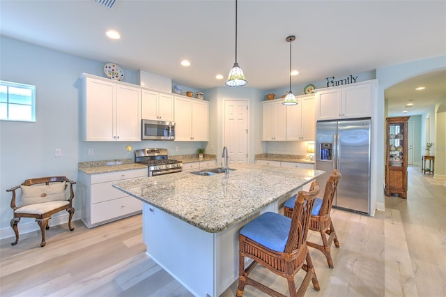 kitchen featuring appliances with stainless steel finishes, white cabinets, hanging light fixtures, and sink