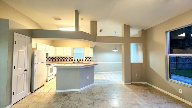 kitchen featuring lofted ceiling, white appliances, tasteful backsplash, light tile patterned flooring, and white cabinetry