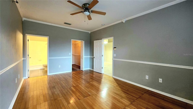 unfurnished bedroom featuring ensuite bath, ornamental molding, ceiling fan, a spacious closet, and a closet