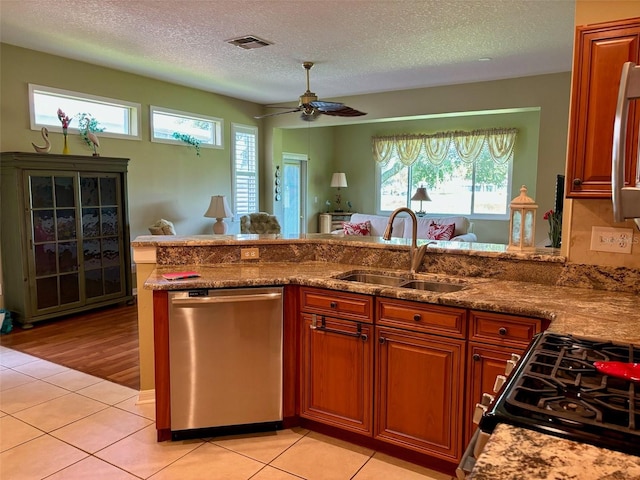 kitchen with stainless steel appliances, light tile patterned flooring, a wealth of natural light, and sink