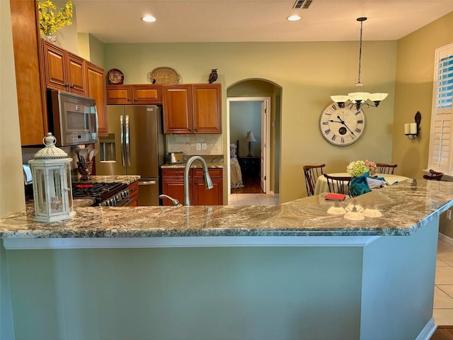 kitchen with light stone counters, stainless steel appliances, light tile patterned floors, and pendant lighting