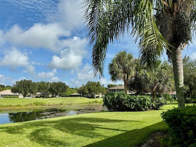 surrounding community with a water view and a lawn