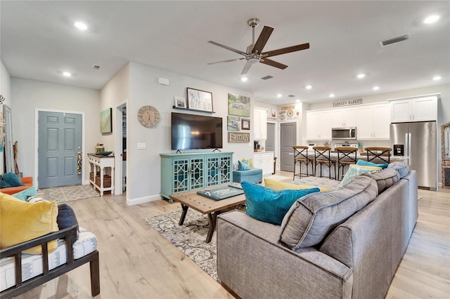 living room featuring ceiling fan and light hardwood / wood-style floors