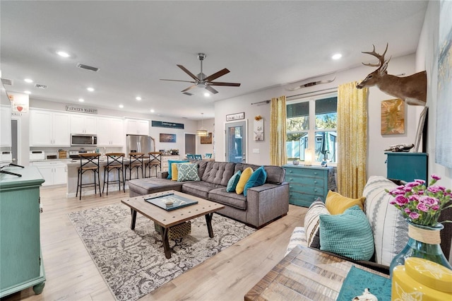 living room featuring light wood-type flooring and ceiling fan