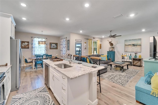 kitchen featuring light hardwood / wood-style floors, a kitchen island with sink, white cabinetry, ceiling fan, and sink