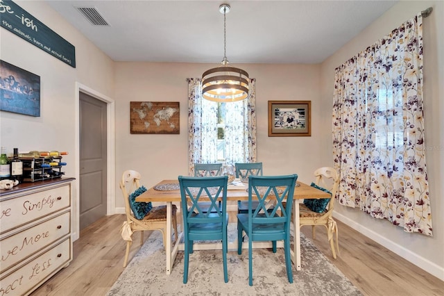 dining area with light wood-type flooring and an inviting chandelier