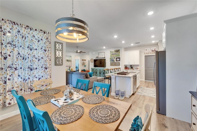 dining space with light wood-type flooring and ceiling fan with notable chandelier