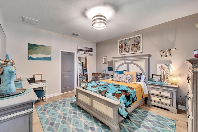 bedroom with a textured ceiling and light hardwood / wood-style floors