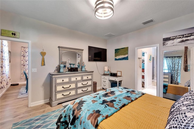 bedroom featuring ensuite bath, a textured ceiling, and light hardwood / wood-style flooring