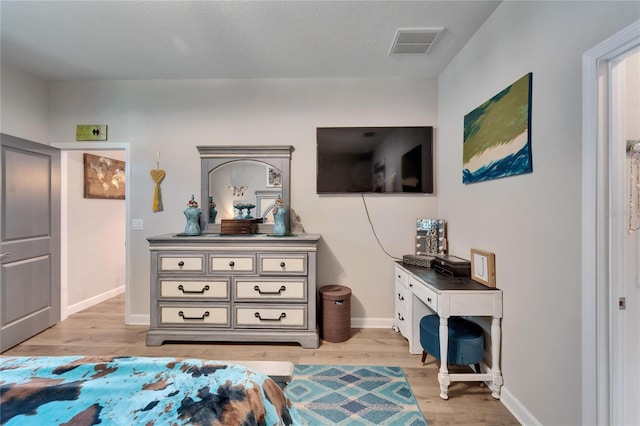 bedroom with a textured ceiling and light hardwood / wood-style floors