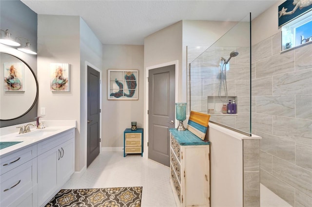 bathroom featuring tile patterned flooring, tiled shower, and vanity