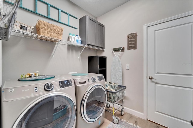 laundry room with light hardwood / wood-style floors, cabinets, and independent washer and dryer