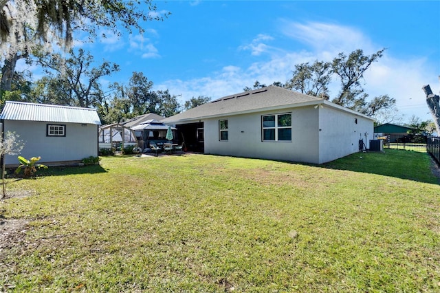 back of house featuring central AC unit, a lawn, and a gazebo