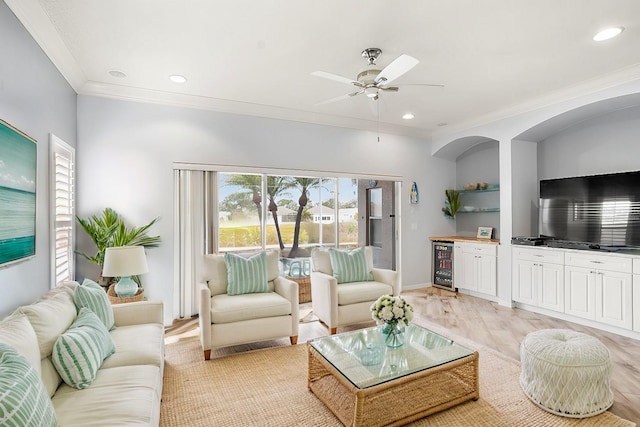 living room with ceiling fan, light hardwood / wood-style flooring, ornamental molding, and wine cooler