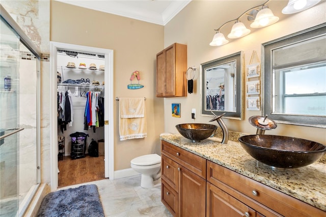 bathroom featuring toilet, ornamental molding, a shower with shower door, and vanity