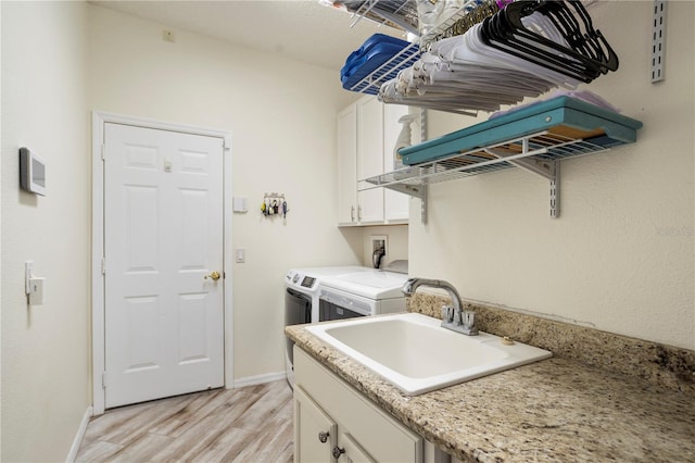 laundry area featuring cabinets, sink, independent washer and dryer, and light hardwood / wood-style floors