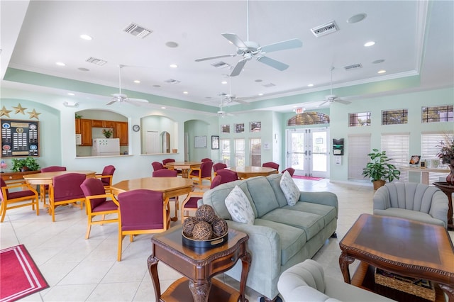 tiled living room with crown molding, a raised ceiling, and french doors