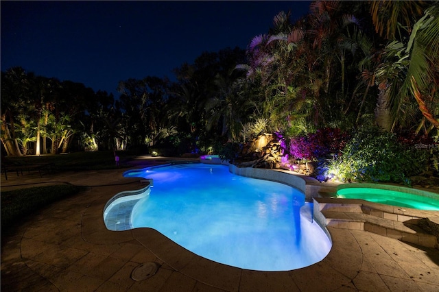 pool at twilight with an outdoor pool and a patio