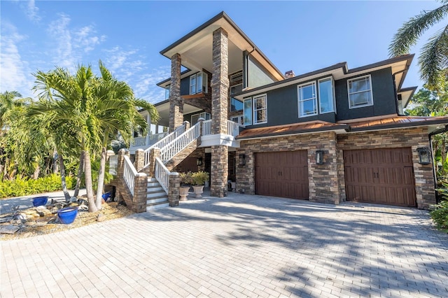 view of front facade featuring stone siding, an attached garage, stairs, decorative driveway, and stucco siding