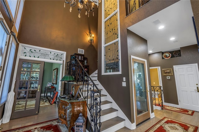 staircase with baseboards, a high ceiling, and visible vents