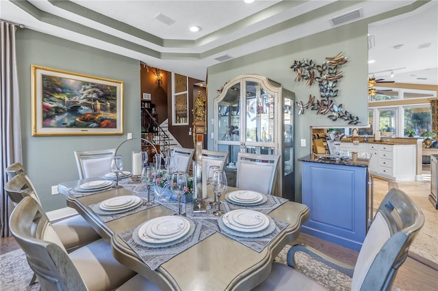 dining space featuring a raised ceiling, visible vents, and a ceiling fan