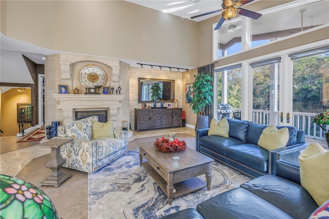 living room with rail lighting, plenty of natural light, a premium fireplace, and high vaulted ceiling