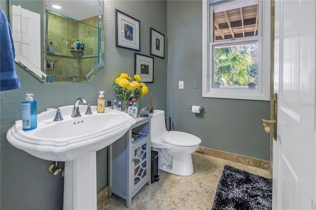 bathroom with a textured wall, a sink, toilet, and baseboards