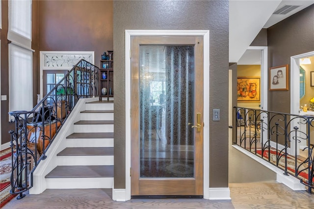 interior space featuring a textured wall, stairway, visible vents, and baseboards