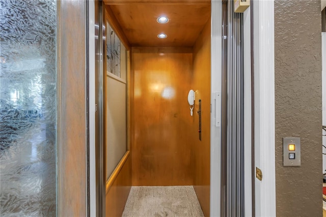 details featuring a textured wall, recessed lighting, and elevator