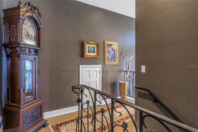 stairway featuring a textured wall, wood finished floors, and baseboards