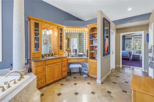 bathroom with lofted ceiling, a garden tub, vanity, baseboards, and decorative columns