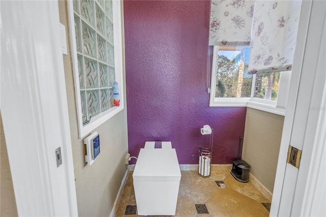 bathroom with a textured wall and baseboards