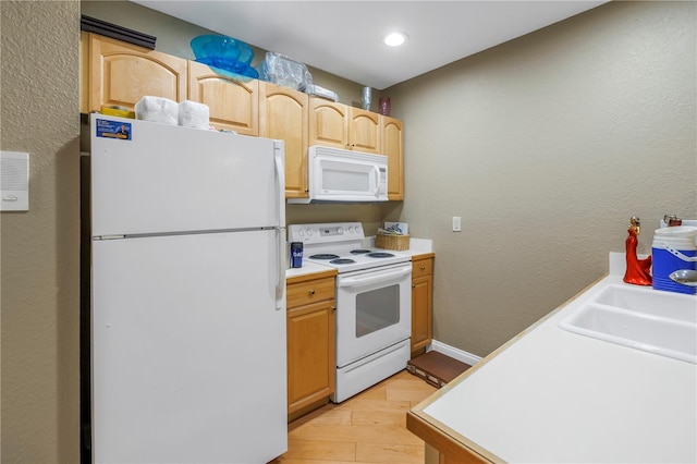 kitchen featuring white appliances, light countertops, light wood-style floors, light brown cabinets, and a sink