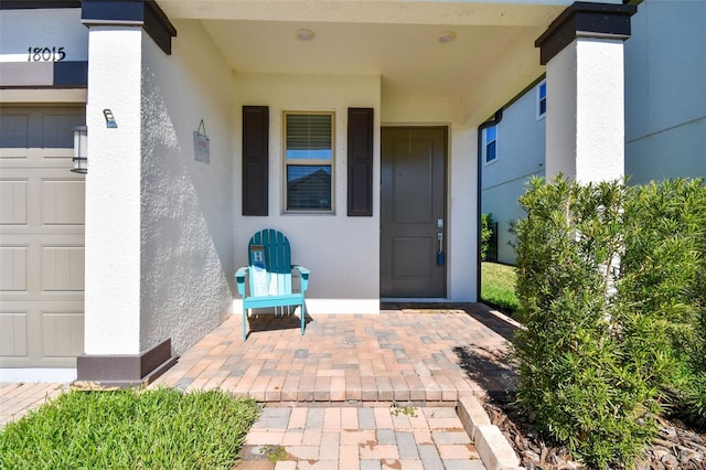 property entrance with a garage and stucco siding