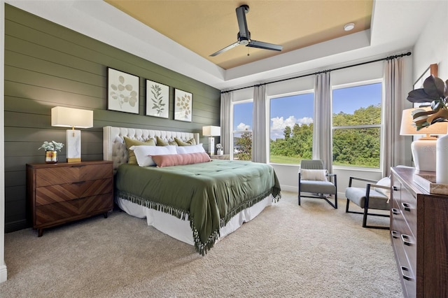 bedroom featuring ceiling fan, a tray ceiling, and light colored carpet