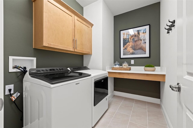 clothes washing area with light tile patterned flooring, cabinets, and washing machine and clothes dryer