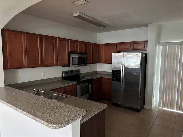 kitchen featuring a kitchen bar, kitchen peninsula, appliances with stainless steel finishes, tile patterned flooring, and sink