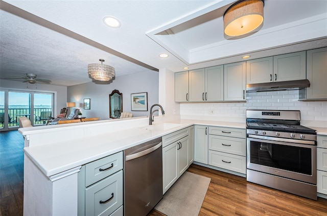 kitchen with kitchen peninsula, stainless steel appliances, ceiling fan, and sink