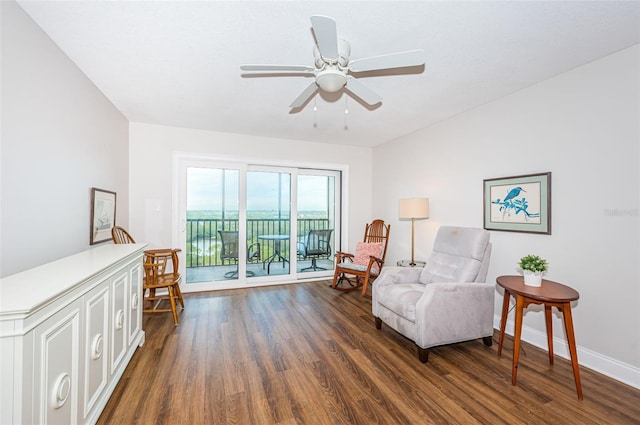 sitting room with ceiling fan and dark wood-type flooring