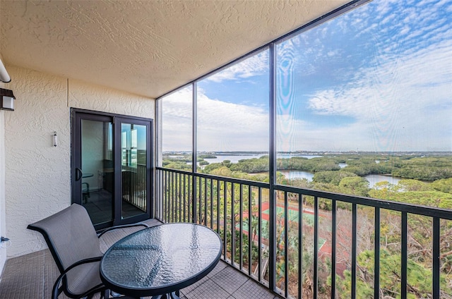 sunroom featuring a water view