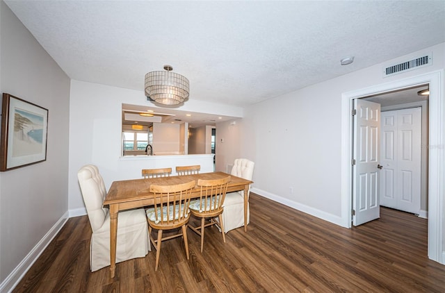 dining space with a textured ceiling, sink, and dark wood-type flooring