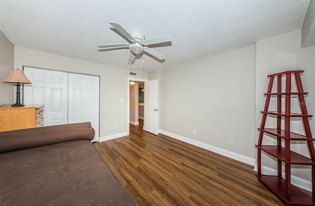 unfurnished bedroom with ceiling fan, dark hardwood / wood-style flooring, a textured ceiling, and a closet