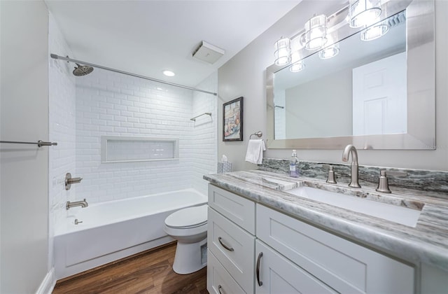 full bathroom featuring hardwood / wood-style flooring, vanity, toilet, and tiled shower / bath