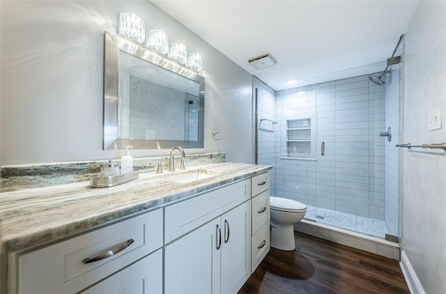 bathroom with walk in shower, vanity, wood-type flooring, and toilet