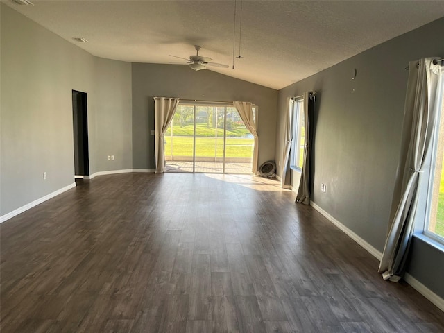 empty room with ceiling fan, vaulted ceiling, dark hardwood / wood-style floors, and a textured ceiling