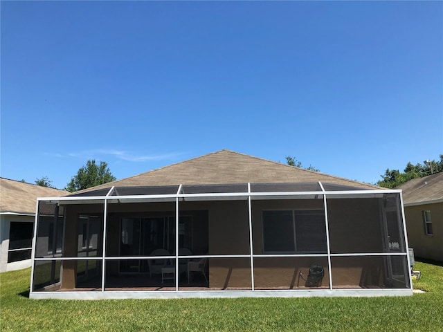 rear view of house featuring a lanai and a lawn