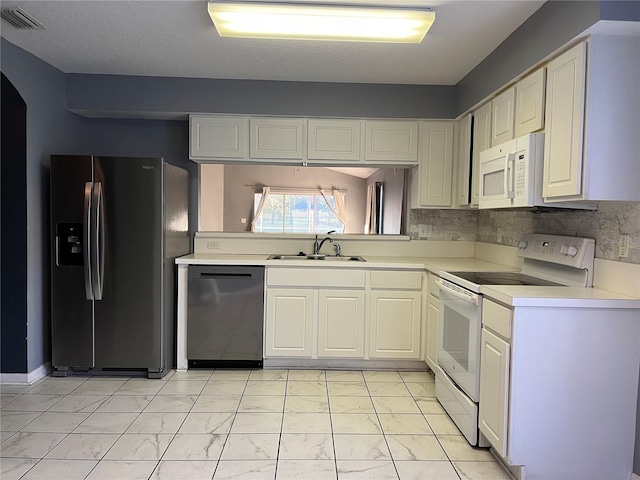 kitchen featuring white cabinetry, sink, white appliances, and backsplash