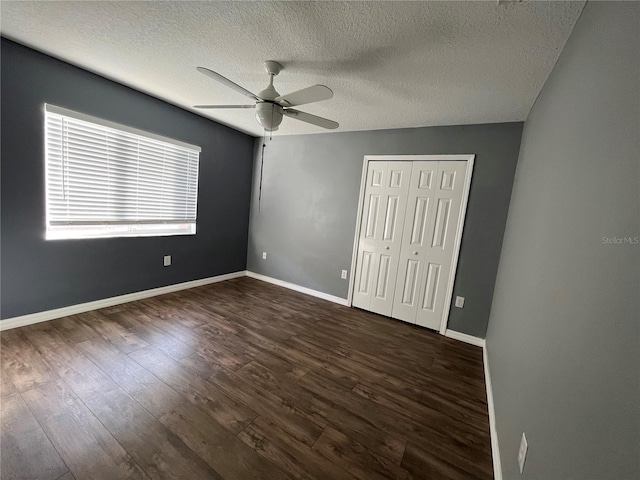 unfurnished bedroom featuring dark wood-type flooring, a textured ceiling, ceiling fan, and a closet