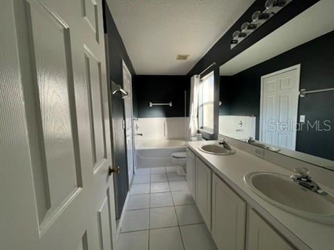 bathroom featuring tile patterned flooring, vanity, a tub, and toilet